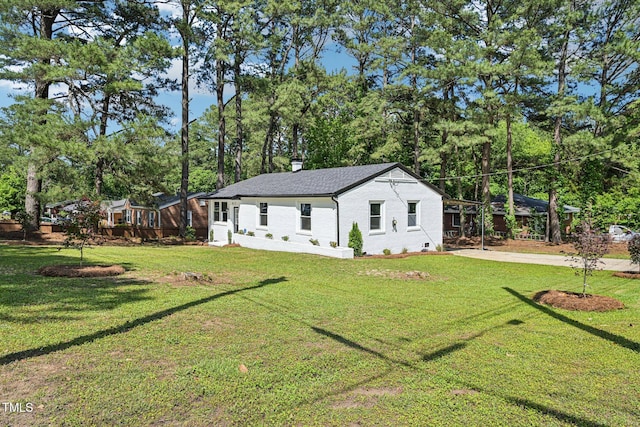 view of front of house with a front yard, brick siding, a chimney, and a shingled roof