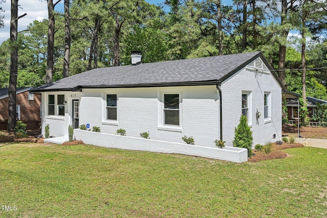 view of front of home featuring brick siding, a chimney, and a front yard