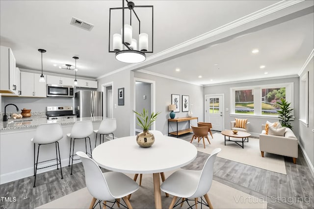 dining area featuring wood finished floors, crown molding, recessed lighting, a chandelier, and baseboards
