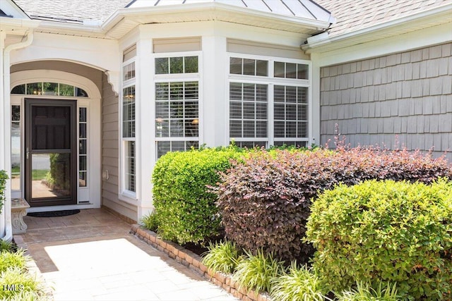 view of exterior entry featuring a shingled roof