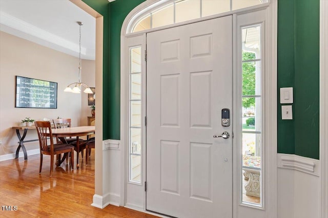 foyer with light wood-type flooring, baseboards, and a chandelier