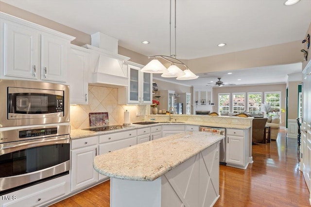 kitchen with appliances with stainless steel finishes, a peninsula, a ceiling fan, white cabinets, and recessed lighting