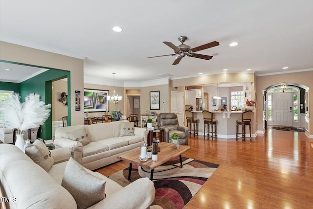 living area featuring a chandelier, light wood-style floors, recessed lighting, ornamental molding, and ceiling fan