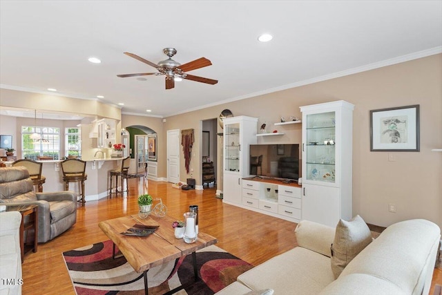 living room with arched walkways, ceiling fan, crown molding, light wood-style flooring, and recessed lighting