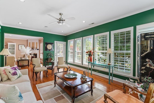 living area with a ceiling fan, wood finished floors, recessed lighting, and crown molding