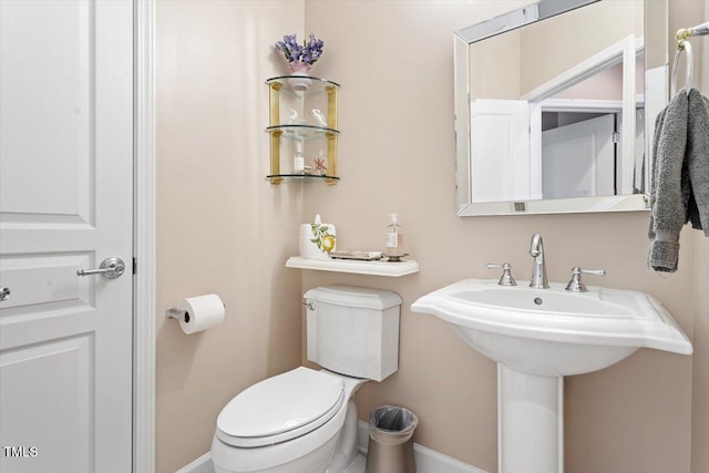half bath featuring toilet and baseboards