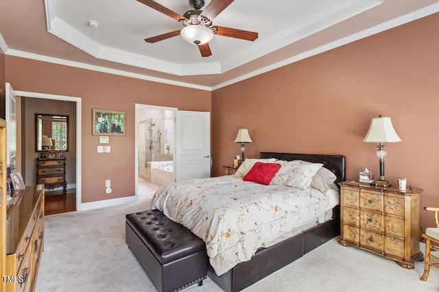 bedroom with light carpet, ornamental molding, ensuite bath, baseboards, and a raised ceiling
