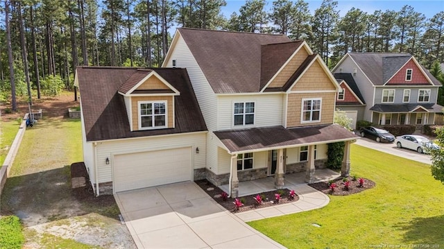 craftsman-style house featuring a porch, driveway, a garage, a front lawn, and stone siding