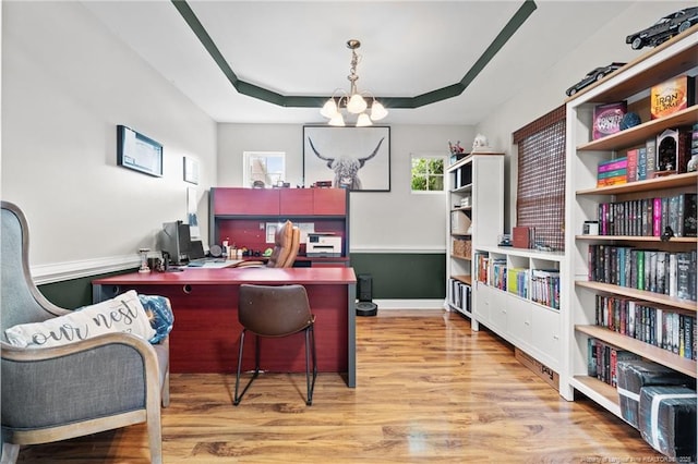 office with a chandelier, wood finished floors, a raised ceiling, and baseboards