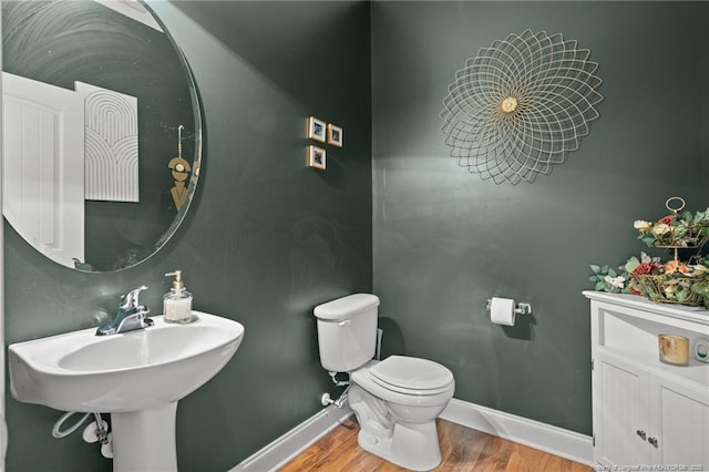 bathroom featuring baseboards, toilet, wood finished floors, and a sink