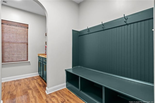 mudroom featuring arched walkways, light wood finished floors, and baseboards