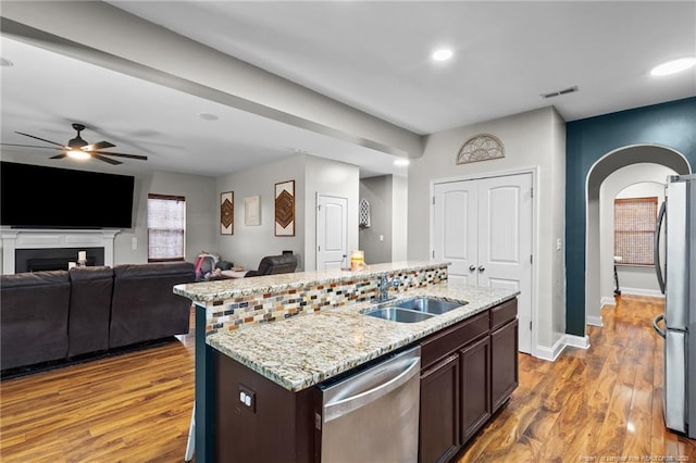 kitchen featuring a sink, stainless steel appliances, ceiling fan, a kitchen island with sink, and dark brown cabinetry