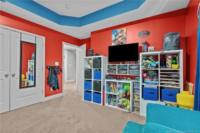 rec room with carpet and a tray ceiling