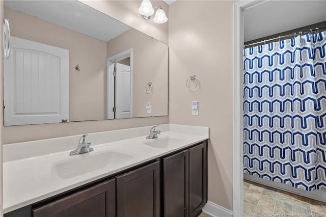 bathroom with double vanity, curtained shower, baseboards, and stone finish floors