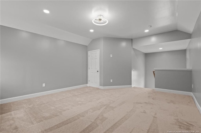 spare room featuring lofted ceiling, carpet flooring, baseboards, and recessed lighting