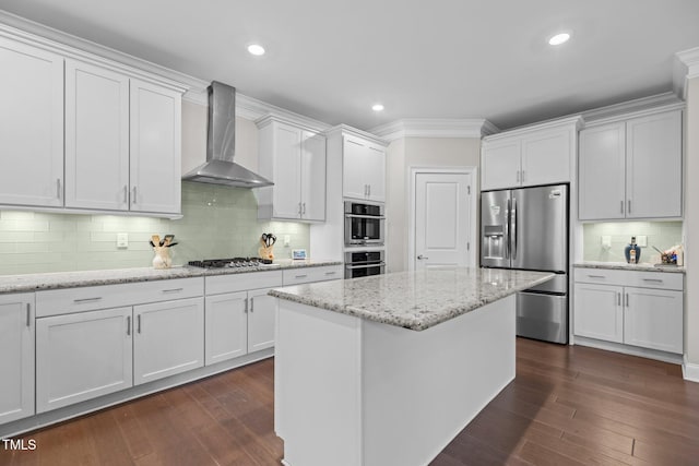 kitchen featuring appliances with stainless steel finishes, wall chimney range hood, white cabinetry, backsplash, and recessed lighting
