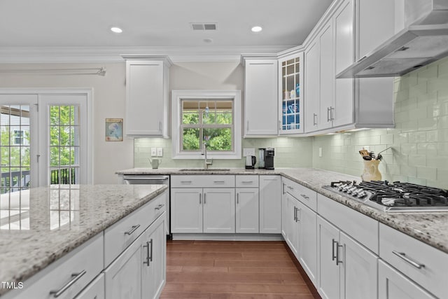 kitchen featuring wall chimney range hood, appliances with stainless steel finishes, dark wood-style floors, white cabinetry, and ornamental molding