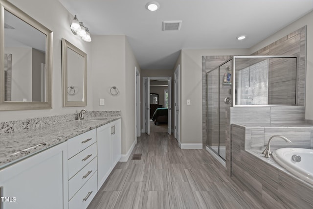 ensuite bathroom featuring plenty of natural light, vanity, a shower stall, a bath, and recessed lighting