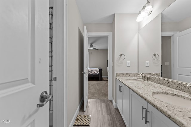 full bath with double vanity, baseboards, ceiling fan, and wood finished floors