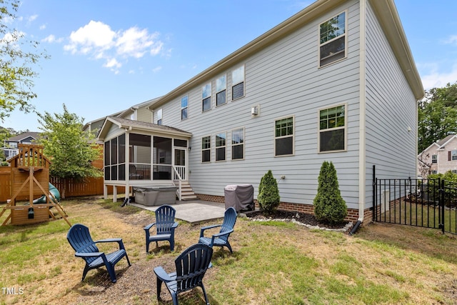 back of property featuring a sunroom, a patio area, a playground, and a hot tub