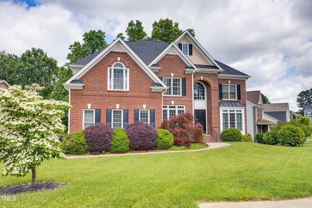 colonial inspired home with brick siding and a front yard