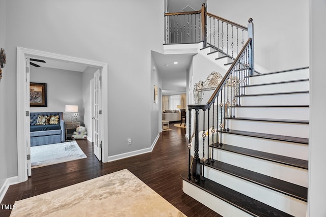entrance foyer featuring wood finished floors, baseboards, stairs, and a high ceiling