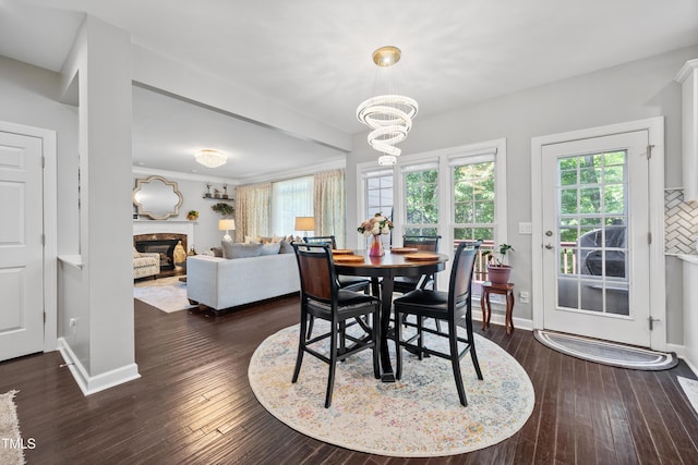 dining area featuring dark wood-style flooring, a premium fireplace, healthy amount of natural light, and a chandelier