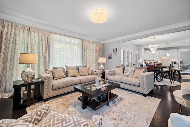 living area with crown molding, a chandelier, and wood finished floors