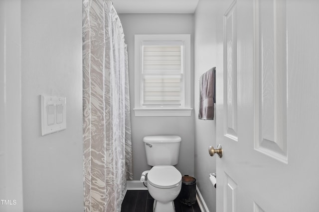bathroom with baseboards, toilet, and a shower with curtain
