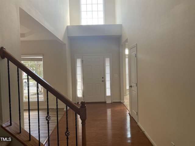 entryway with wood finished floors, stairs, a high ceiling, and baseboards