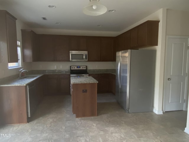 kitchen featuring appliances with stainless steel finishes, a sink, and a center island