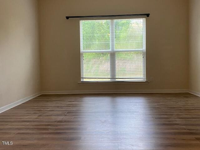 unfurnished room featuring plenty of natural light, wood finished floors, and baseboards