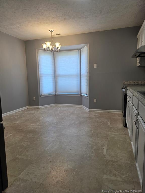 2604 Burke Ln, Fayetteville, NC 28306 - kitchen with a chandelier, a textured ceiling, white cabinetry, baseboards, and hanging light fixtures