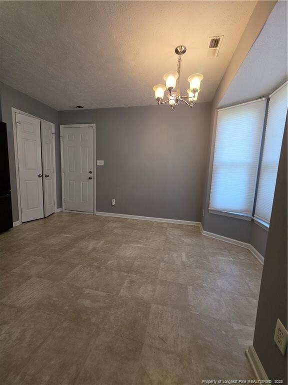 2604 Burke Ln, Fayetteville, NC 28306 - spare room featuring a chandelier, baseboards, and a textured ceiling