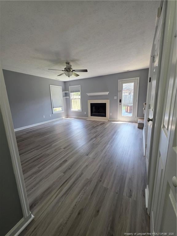 2604 Burke Ln, Fayetteville, NC 28306 - unfurnished living room with dark wood-style flooring, baseboards, a textured ceiling, healthy amount of natural light, and ceiling fan