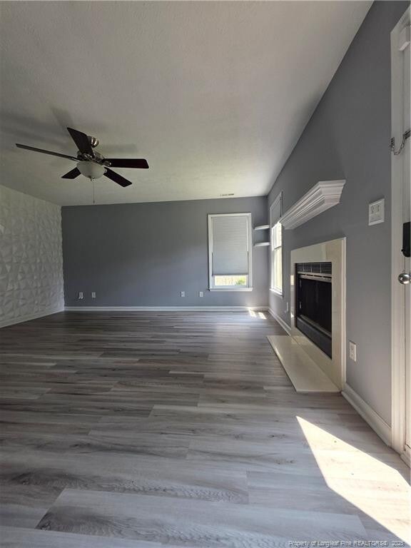 2604 Burke Ln, Fayetteville, NC 28306 - unfurnished living room featuring a fireplace with flush hearth, wood finished floors, a ceiling fan, and baseboards