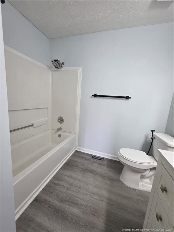 2604 Burke Ln, Fayetteville, NC 28306 - full bathroom with vanity, wood finished floors, shower / bath combination, toilet, and a textured ceiling
