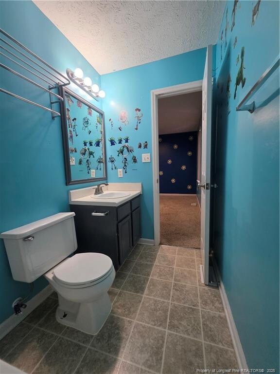 2604 Burke Ln, Fayetteville, NC 28306 - bathroom featuring toilet, a textured ceiling, vanity, and baseboards