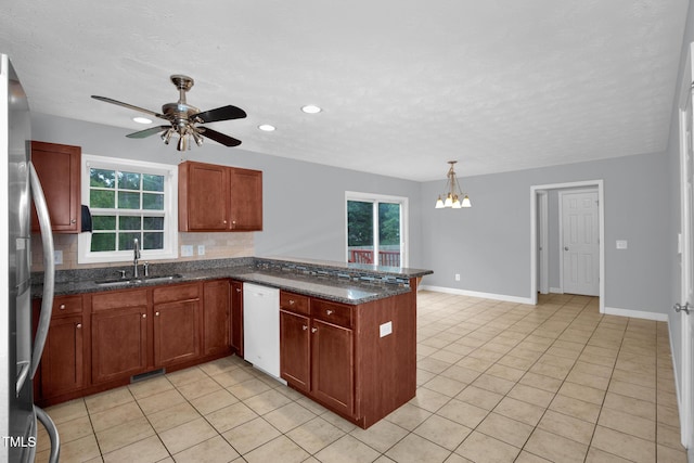 kitchen featuring a sink, dishwasher, a peninsula, light tile patterned floors, and a textured ceiling