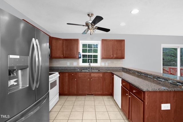 kitchen with white appliances, a sink, a peninsula, backsplash, and light tile patterned floors