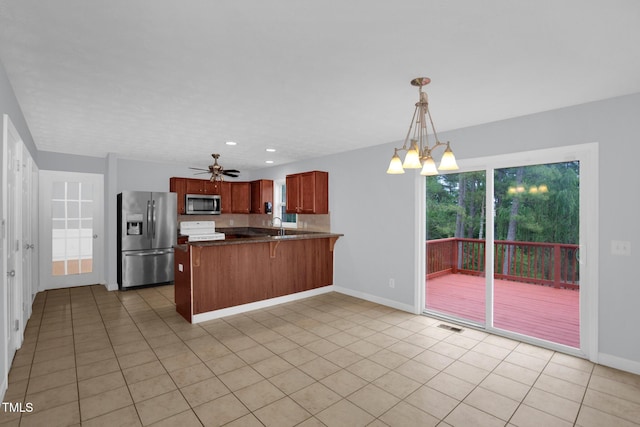 kitchen with stainless steel appliances, a peninsula, a chandelier, baseboards, and a sink