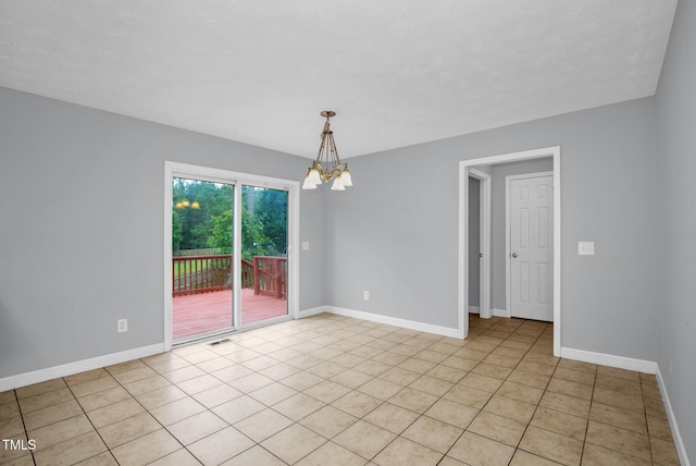 empty room featuring a chandelier, baseboards, and light tile patterned flooring