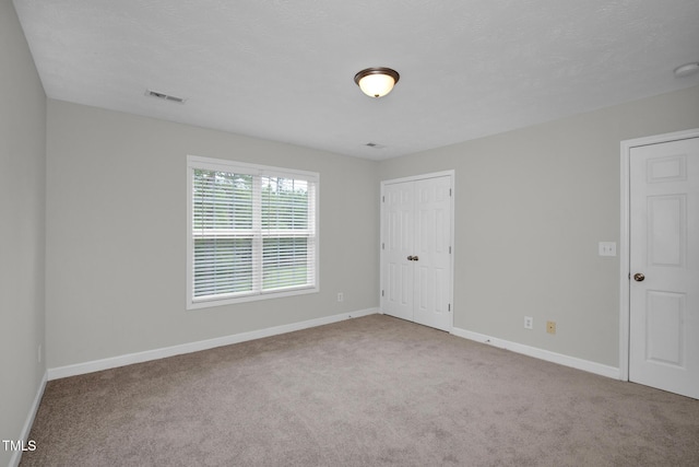 carpeted empty room featuring baseboards and a smoke detector