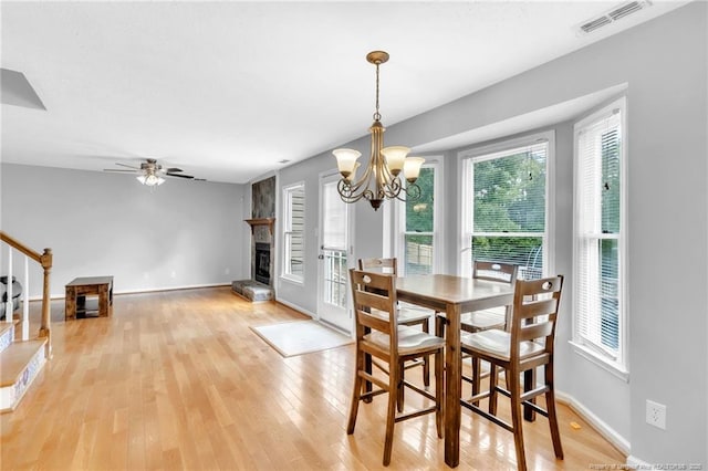 4725 Grandison Ct, Hope Mills, NC 28348 - dining room featuring a fireplace with raised hearth, light wood-style floors, a chandelier, baseboards, and ceiling fan