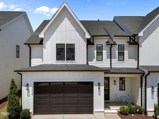 view of front of house with board and batten siding, an attached garage, covered porch, and roof with shingles