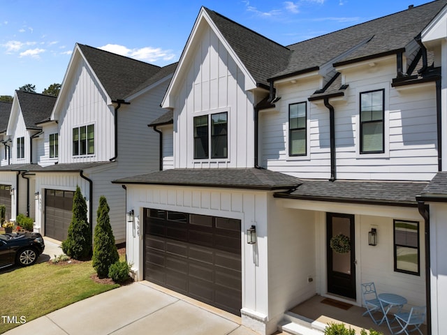 view of property with board and batten siding, an attached garage, concrete driveway, and a shingled roof