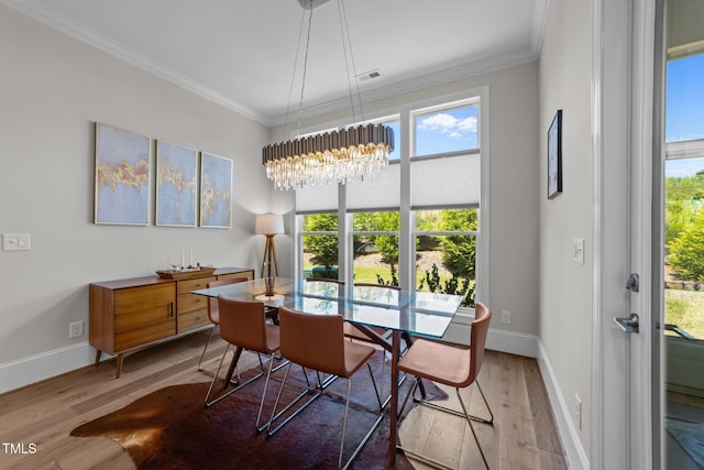dining space with wood finished floors, crown molding, a chandelier, and baseboards