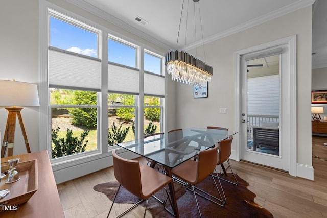 dining space featuring crown molding, wood-type flooring, a chandelier, and baseboards