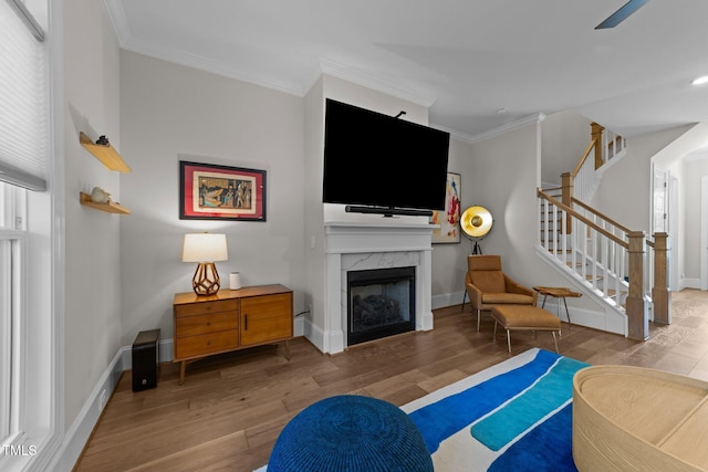 living area with wood finished floors, stairs, ornamental molding, a fireplace, and baseboards