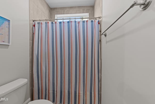 bathroom featuring toilet and curtained shower